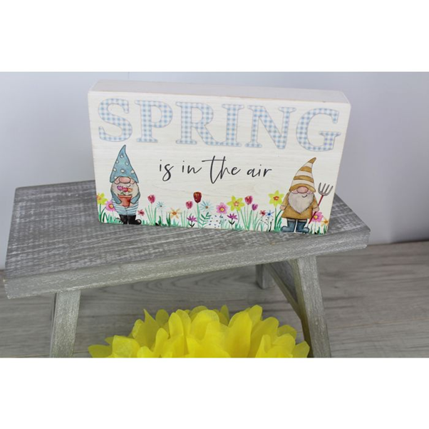 Decorative spring display sign with illustrated Easter gonks placed on a wooden stool in a seasonal gift shop setting. 