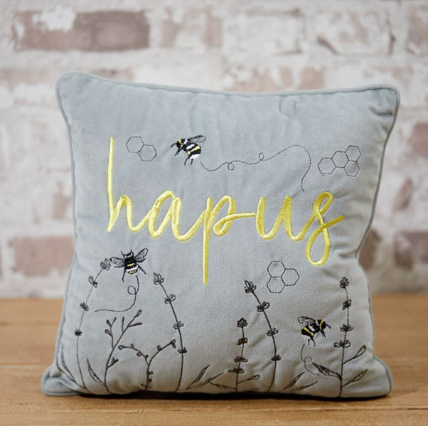 Bee cushion with nature-inspired design placed on a sofa, enhancing home decor with a botanical theme.