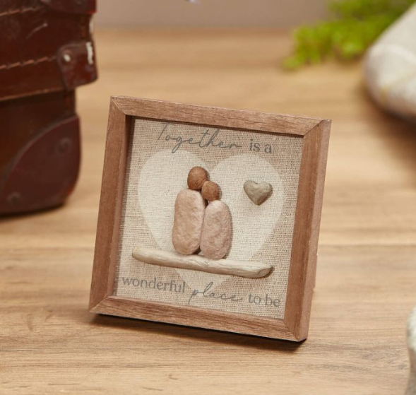Small framed pebble art displaying two heart-shaped pebbles with text 